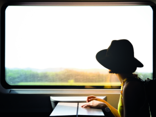 A beautiful hipster asian woman travelling on the train. Sitting on the black leather cozy comfort seat in the business class boky of the train in Europe. Tourist travel concept.; Shutterstock ID 1111543499; Purchase Order: -