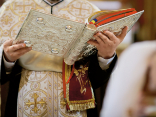Bucharest, Romania - May 24, 2020: Details of an Orthodox priest reading from the Holy Bible during an Orthodox Baptism.